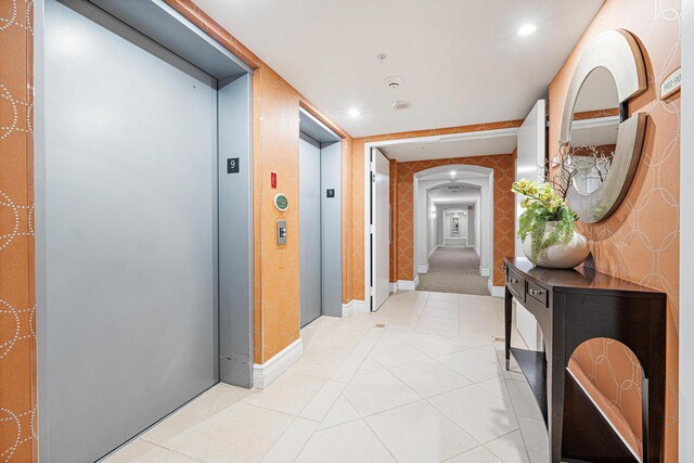 hall featuring light tile patterned flooring and elevator