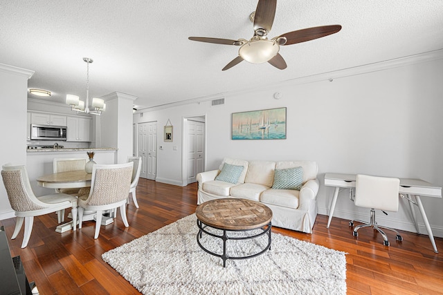 living room featuring ornamental molding, a textured ceiling, ceiling fan with notable chandelier, and dark hardwood / wood-style floors