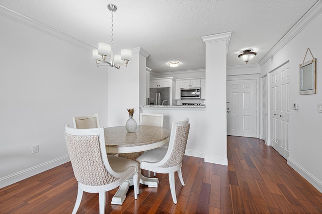 dining area featuring a textured ceiling, dark wood-style flooring, baseboards, ornamental molding, and an inviting chandelier