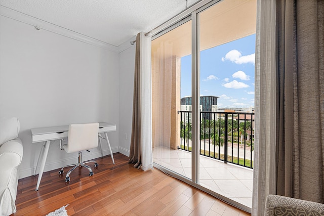 office area with floor to ceiling windows, crown molding, a textured ceiling, wood finished floors, and baseboards