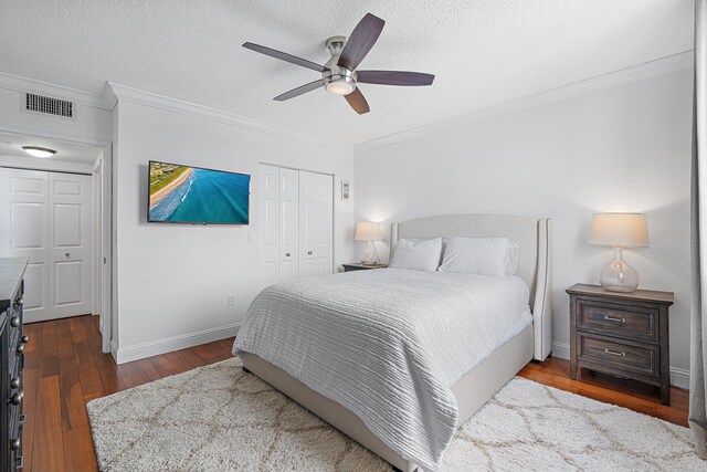 bedroom featuring dark hardwood / wood-style flooring, a textured ceiling, ceiling fan, and crown molding