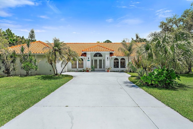 mediterranean / spanish home featuring a front lawn and french doors