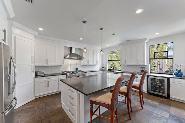 kitchen featuring wine cooler, stainless steel appliances, wall chimney exhaust hood, dark countertops, and pendant lighting