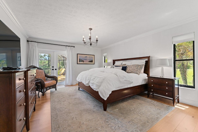 bedroom with a textured ceiling, light wood-style floors, access to outside, french doors, and crown molding