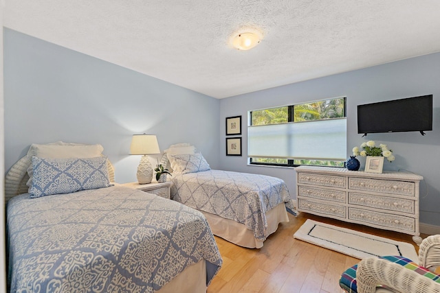 bedroom with light wood-type flooring and a textured ceiling