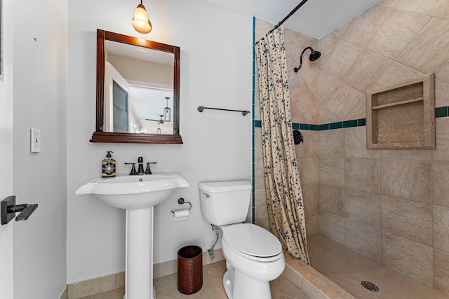 bathroom with tile patterned flooring, toilet, a sink, baseboards, and a stall shower