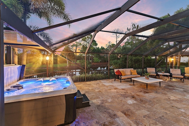 patio terrace at dusk with outdoor lounge area, a hot tub, and a lanai