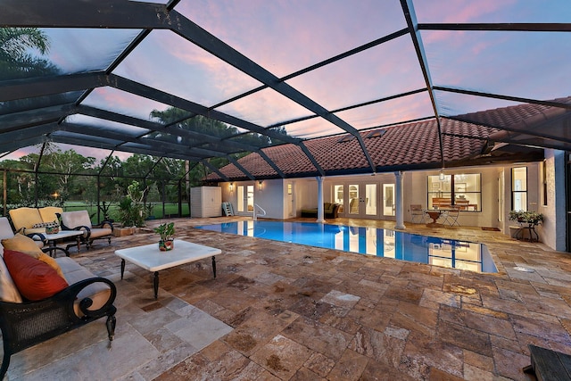 pool at dusk featuring an outbuilding, an outdoor hangout area, a patio area, a lanai, and an outdoor pool