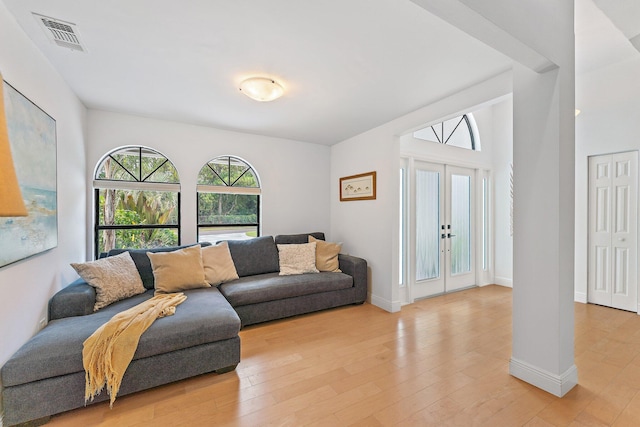 living room featuring french doors, lofted ceiling, visible vents, light wood-style flooring, and baseboards