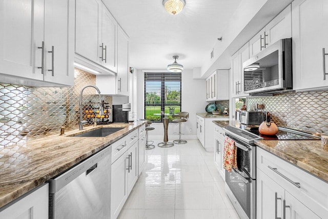 kitchen featuring backsplash, dishwasher, sink, range, and white cabinets