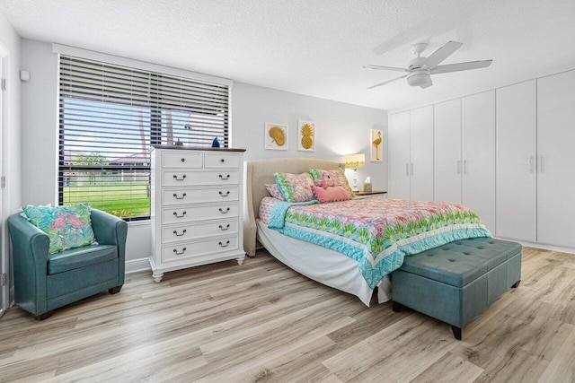 bedroom featuring light hardwood / wood-style floors, ceiling fan, and a textured ceiling