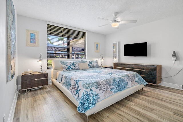 bedroom with hardwood / wood-style floors, a textured ceiling, and ceiling fan