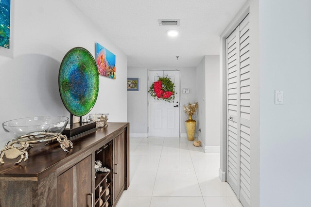 corridor featuring a textured ceiling and light tile patterned floors