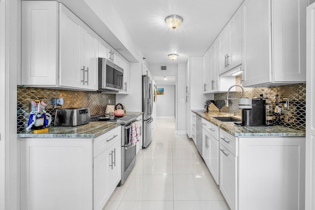 kitchen with decorative backsplash, stainless steel appliances, white cabinetry, and sink