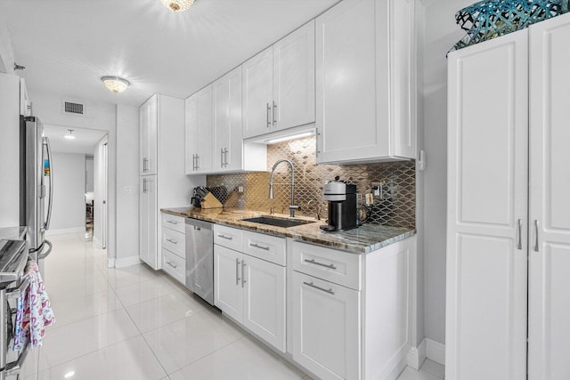 kitchen featuring sink, stainless steel appliances, white cabinets, and light stone counters