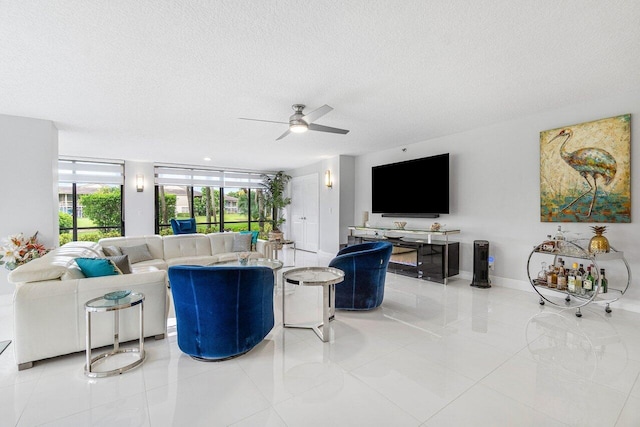 tiled living room featuring ceiling fan, a textured ceiling, and a wall of windows