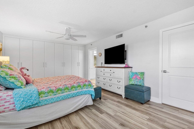 bedroom with light hardwood / wood-style floors, ceiling fan, and a textured ceiling