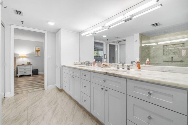 bathroom with a shower with shower door, vanity, and tile patterned floors