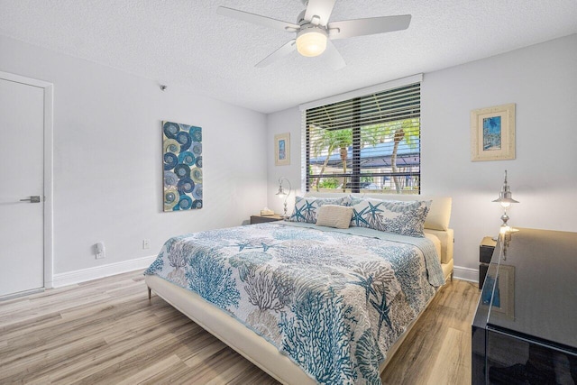 bedroom with a textured ceiling, ceiling fan, and hardwood / wood-style floors