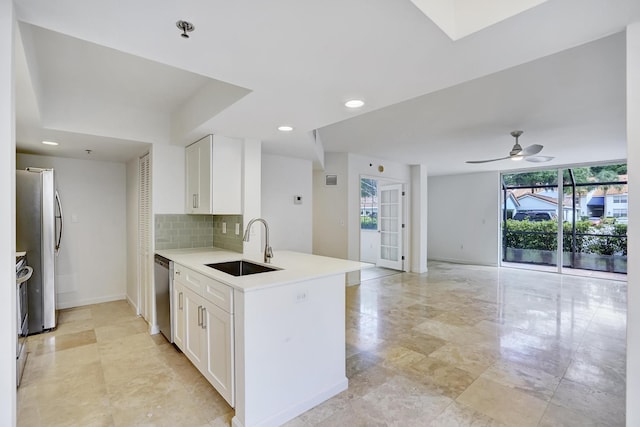 kitchen featuring stainless steel appliances, light countertops, a sink, and white cabinetry