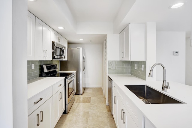 kitchen featuring stainless steel appliances, light countertops, white cabinetry, and a sink