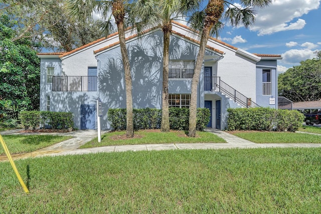 view of front of house featuring a front yard, a tile roof, and stairway