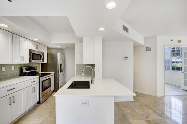 kitchen featuring appliances with stainless steel finishes, light countertops, white cabinets, and a sink