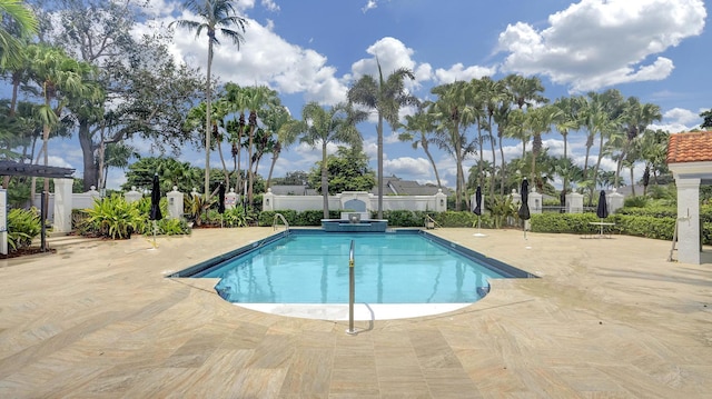 view of swimming pool with a pool with connected hot tub, a patio, and fence