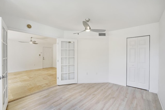 unfurnished room featuring french doors, light wood-style flooring, visible vents, and a ceiling fan