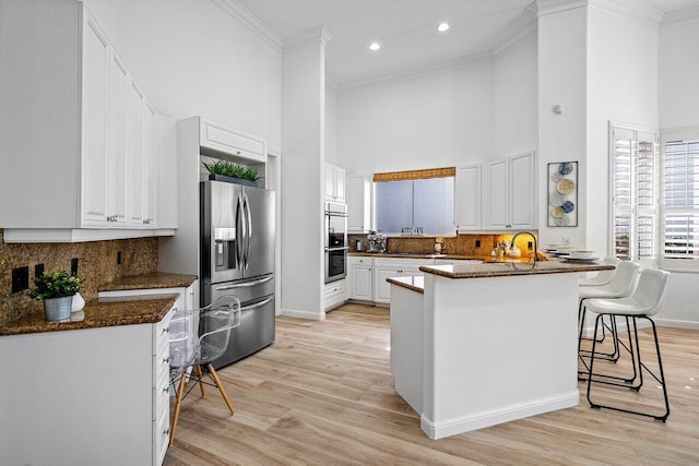 kitchen featuring white cabinetry, kitchen peninsula, appliances with stainless steel finishes, a breakfast bar area, and light hardwood / wood-style flooring