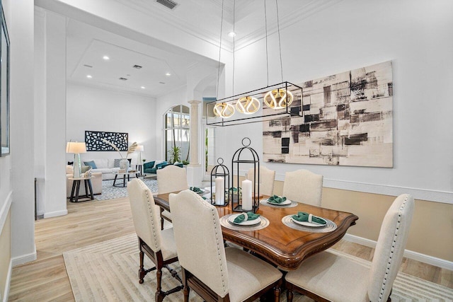 dining room with ornate columns, light wood-type flooring, and ornamental molding