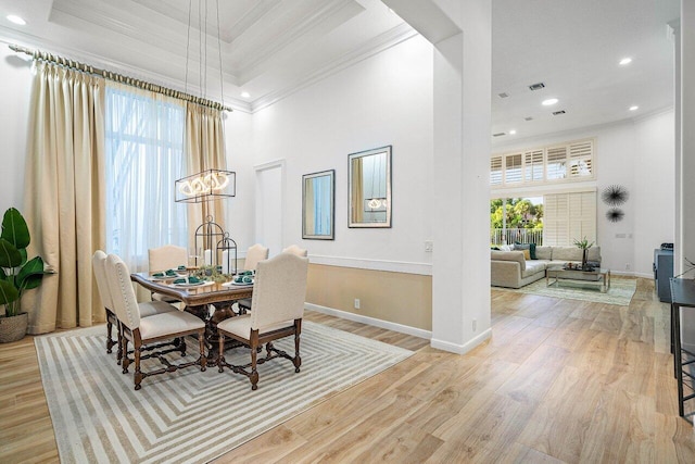 dining room featuring ornamental molding, light hardwood / wood-style flooring, a healthy amount of sunlight, and a high ceiling