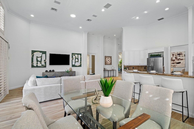 dining room with light wood-type flooring, a wealth of natural light, and crown molding