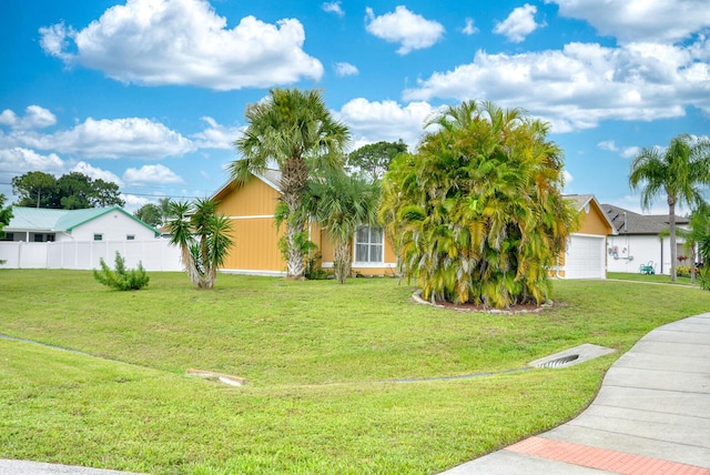 view of property hidden behind natural elements with fence and a front lawn