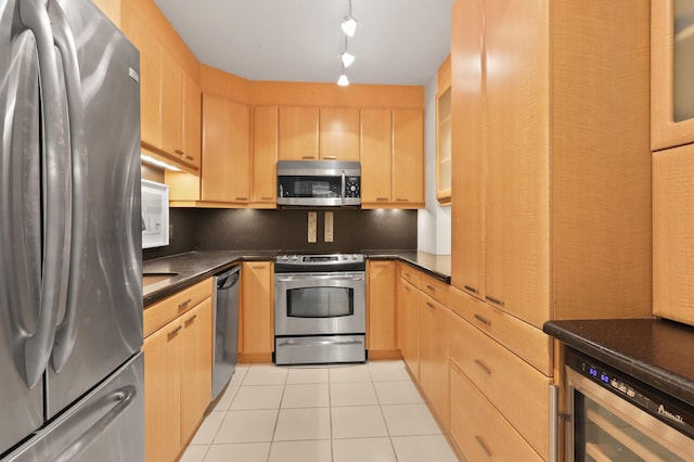 kitchen with light tile patterned floors, beverage cooler, dark countertops, appliances with stainless steel finishes, and backsplash