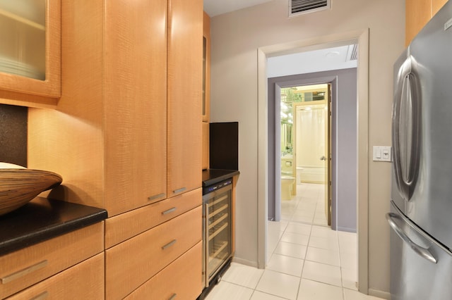 kitchen with light tile patterned floors, beverage cooler, freestanding refrigerator, dark countertops, and glass insert cabinets