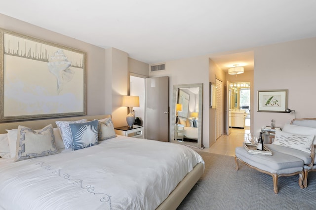 bedroom featuring light tile patterned floors, ensuite bath, and visible vents