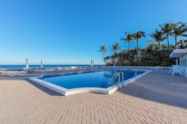 community pool with a patio and a water view