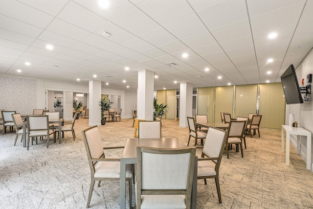 carpeted dining space with a drop ceiling