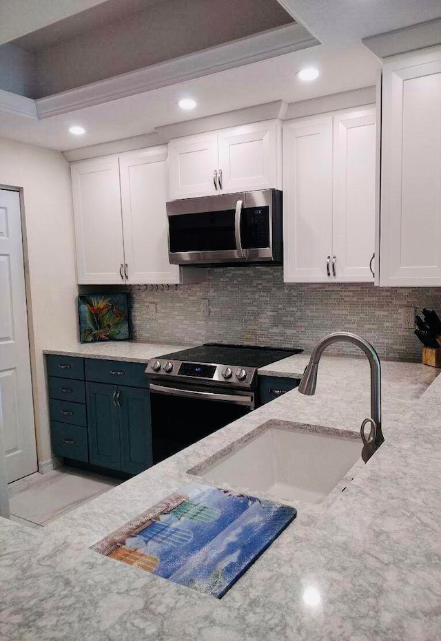 kitchen featuring tasteful backsplash, white cabinets, stainless steel appliances, sink, and a raised ceiling