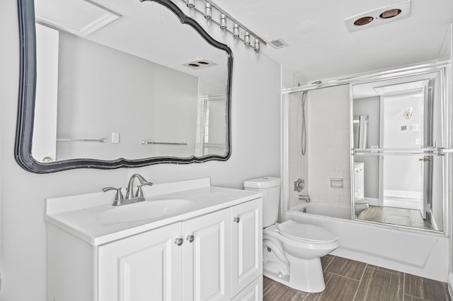 full bathroom featuring bath / shower combo with glass door, vanity, and toilet