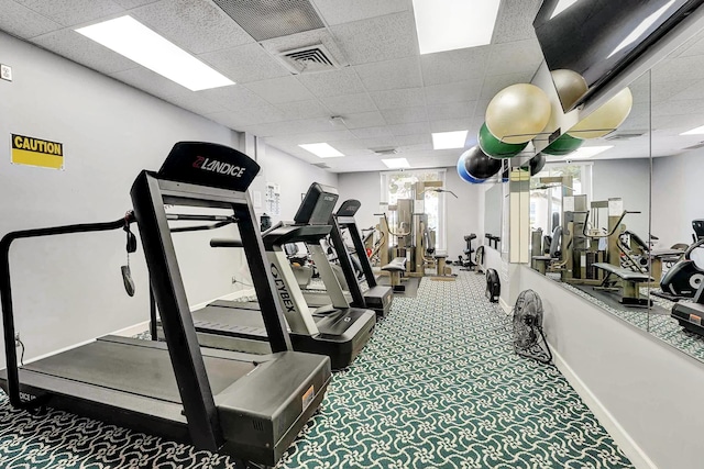 exercise room featuring a paneled ceiling and carpet