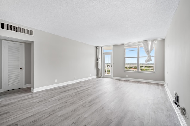 unfurnished room featuring a textured ceiling and light wood-type flooring