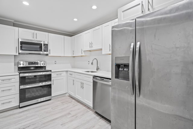 kitchen with sink, appliances with stainless steel finishes, white cabinetry, backsplash, and light hardwood / wood-style floors