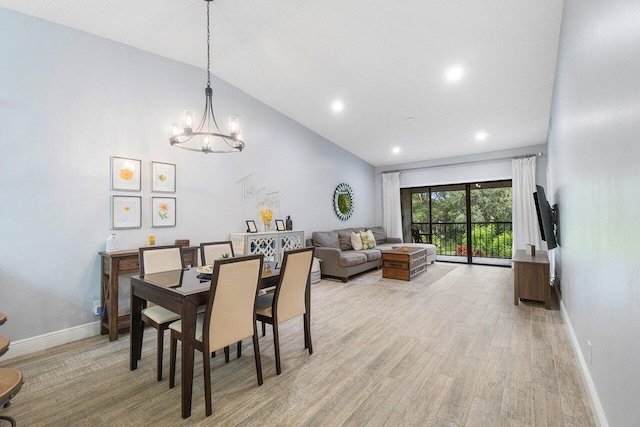 dining area with light hardwood / wood-style floors, an inviting chandelier, and high vaulted ceiling