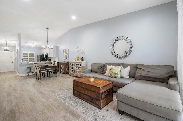 living room featuring vaulted ceiling, light hardwood / wood-style flooring, and an inviting chandelier