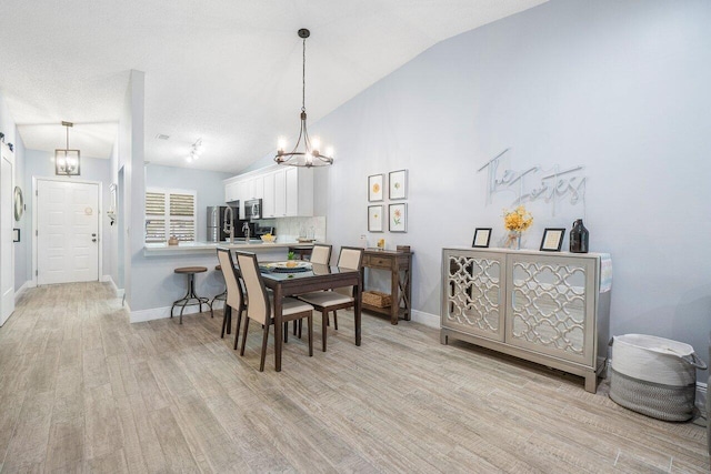 dining area featuring an inviting chandelier, light hardwood / wood-style flooring, and vaulted ceiling