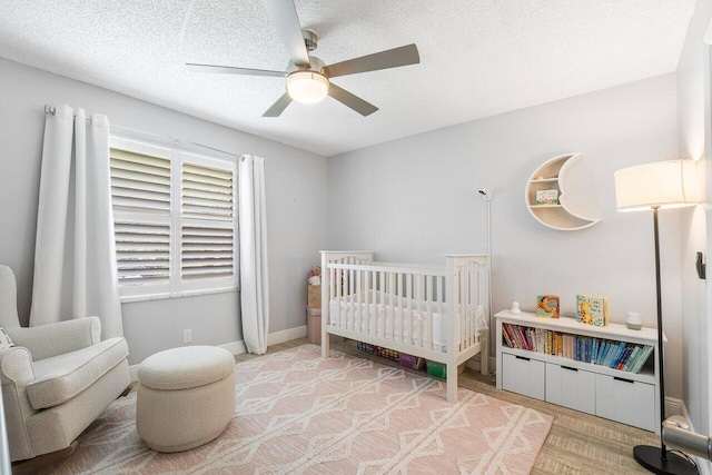 bedroom with a crib, a textured ceiling, and ceiling fan