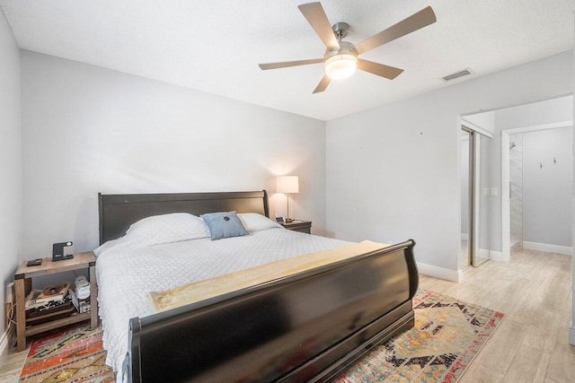 bedroom with a textured ceiling, ceiling fan, and light wood-type flooring