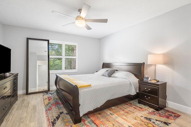 bedroom with light wood-type flooring, ceiling fan, and a textured ceiling